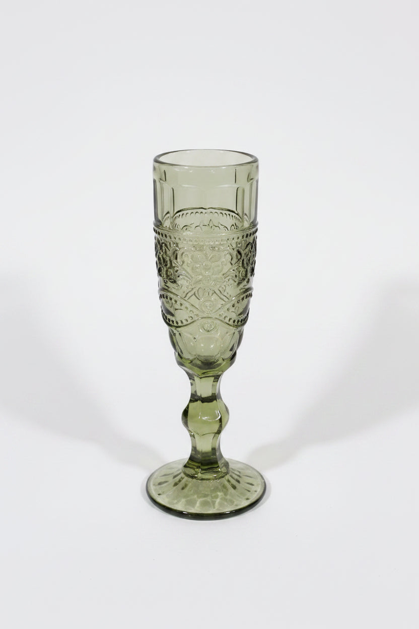 Green glass goblet with intricate design on a white background
